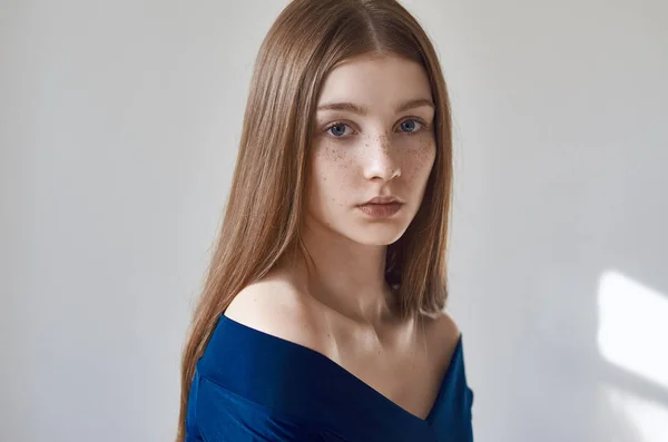 Tema da beleza: retrato de uma bela jovem com sardas em seu rosto e vestindo um vestido azul em um fundo branco no estúdio — Fotografia de Stock