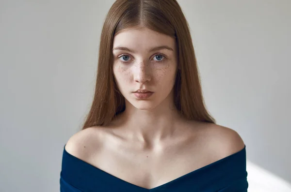 Tema de belleza: retrato de una hermosa joven con pecas en la cara y con un vestido azul sobre un fondo blanco en el estudio —  Fotos de Stock