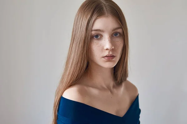 Tema di bellezza: ritratto di una bella ragazza con le lentiggini sul viso e indossa un vestito blu su sfondo bianco in studio — Foto Stock