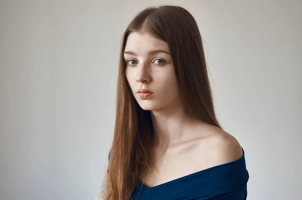 Tema da beleza: retrato de uma bela jovem com sardas em seu rosto e vestindo um vestido azul em um fundo branco no estúdio — Fotografia de Stock