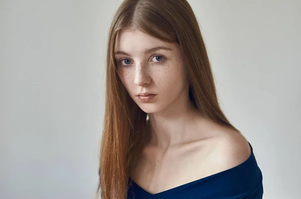 Schönheitsthema: Porträt eines schönen jungen Mädchens mit Sommersprossen im Gesicht und einem blauen Kleid auf weißem Hintergrund im Atelier — Stockfoto
