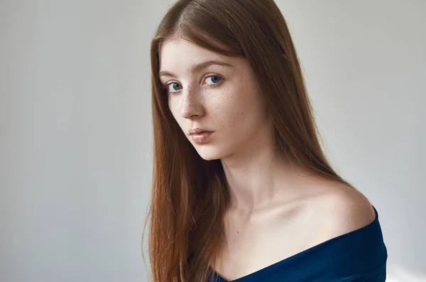 Tema da beleza: retrato de uma bela jovem com sardas em seu rosto e vestindo um vestido azul em um fundo branco no estúdio — Fotografia de Stock