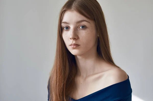 Tema de belleza: retrato de una hermosa joven con pecas en la cara y con un vestido azul sobre un fondo blanco en el estudio —  Fotos de Stock