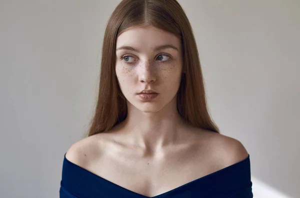 Tema de belleza: retrato de una hermosa joven con pecas en la cara y con un vestido azul sobre un fondo blanco en el estudio — Foto de Stock