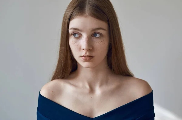 Tema de belleza: retrato de una hermosa joven con pecas en la cara y con un vestido azul sobre un fondo blanco en el estudio — Foto de Stock