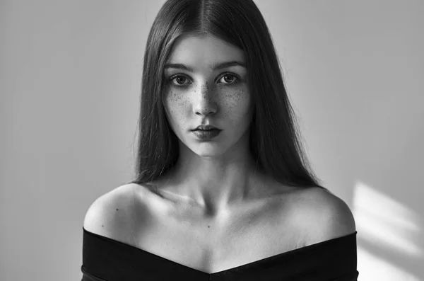 Drammatico ritratto in bianco e nero di una bella ragazza solitaria con lentiggini isolate su uno sfondo bianco in studio girato — Foto Stock