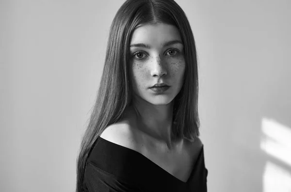 Dramatic black and white portrait of a beautiful lonely girl with freckles isolated on a white background in studio shot — Stock Photo, Image