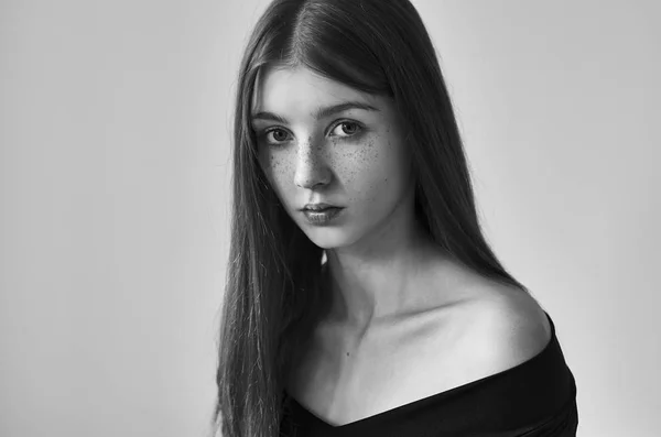 Dramatic black and white portrait of a beautiful lonely girl with freckles isolated on a white background in studio shot — Stock Photo, Image