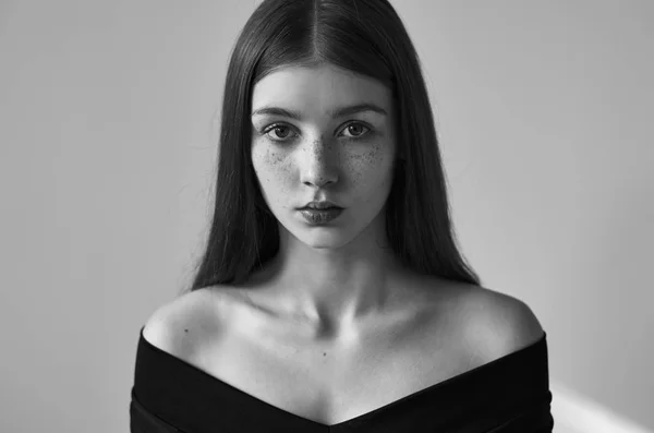 Dramatic black and white portrait of a beautiful lonely girl with freckles isolated on a white background in studio shot — Stock Photo, Image