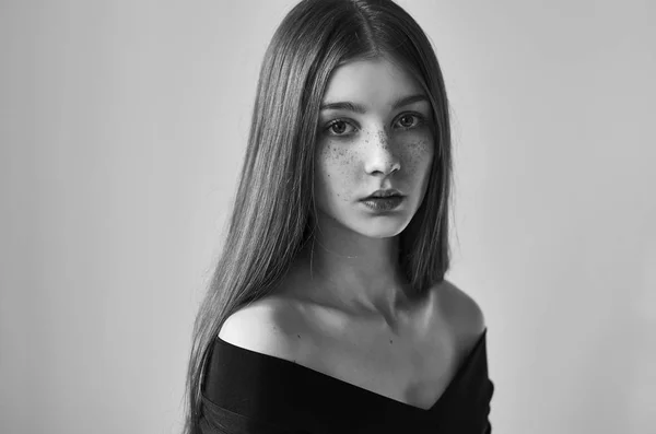 Drammatico ritratto in bianco e nero di una bella ragazza solitaria con lentiggini isolate su uno sfondo bianco in studio girato — Foto Stock