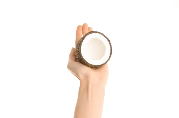 Тема: Human hand holding a half of coconut isolated on a white background in the studio, first-person view — стоковое фото