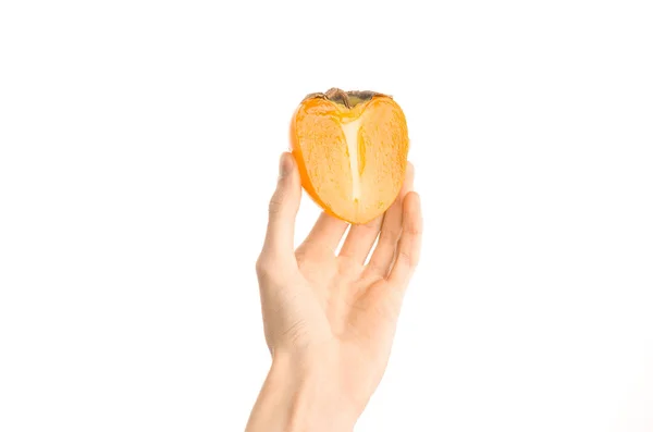 Тема: Human hand holding a half of persimmons isolated on white background in the studio, first-person view — стоковое фото