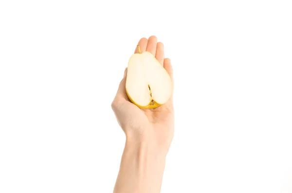 Тема: Human hand holds half of pear isolated on a white background in the studio, first-person view — стоковое фото