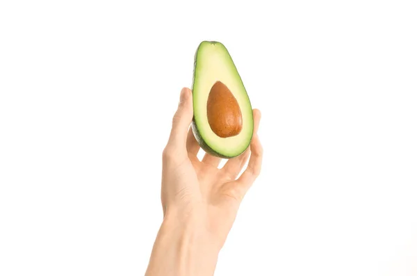 Healthy eating and diet Topic: Human hand holding a half avocado isolated on a white background in the studio, first-person view — Stock Photo, Image