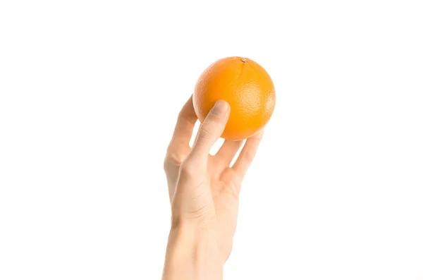 Тема: Human hand holds a ripe orange isolated on a white background in the studio, first-person view — стоковое фото