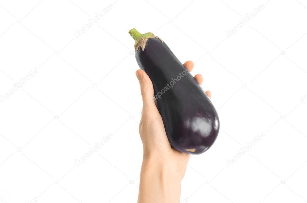 Healthy eating and diet Topic: Human hand holding a ripe eggplant isolated on a white background in the studio, first-person view