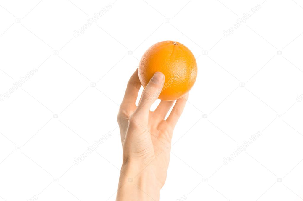 Healthy eating and diet Topic: Human hand holds a ripe orange isolated on a white background in the studio, first-person view