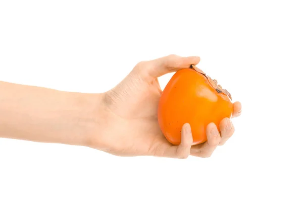 Тема: Human hand holding a ripe persimmon isolated on a white background in the studio — стоковое фото