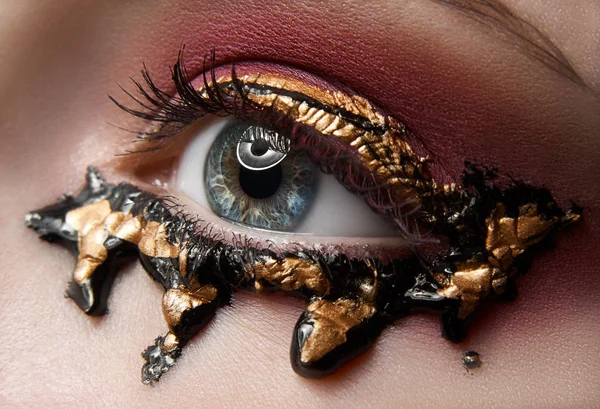 Makro- und Nahaufnahme kreatives Make-up-Thema: schöne weibliche Augen mit roten Schatten und Gold, schwarze Farbe, retuschiertes Foto — Stockfoto