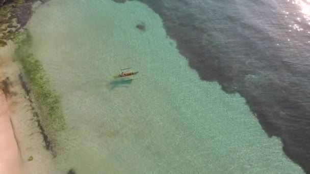 Imagens de drones de um homem é um barco de caiaque da costa arenosa ao longo da água azul-turquesa ao nascer do sol. Vista superior cinematográfica — Vídeo de Stock