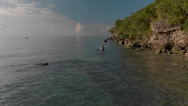 Långsam flygning över klart vatten nära en stenig strand. Filmsyn — Stockvideo