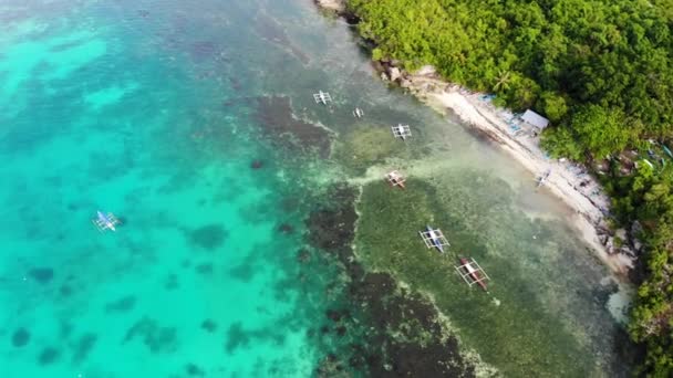 Drone aéreo tiro cinematográfico de pequena praia de areia com pequenos barcos e costa de coral com água cristalina turquesa — Vídeo de Stock