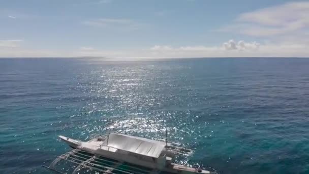 Barco turístico blanco en el mar azul tranquilo cerca de la playa de arena. Lanzamiento aéreo de drones cinematográficos — Vídeo de stock