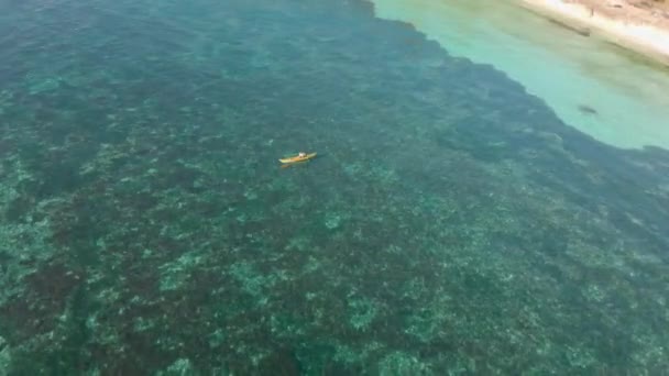 サンゴ礁と驚くほど穏やかなクリスタル澄んだ海の水の上にボートの空中映画トップドローンショット. — ストック動画