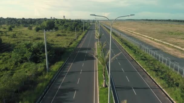 Motorcyclists ride on the freeway. Cinematic drone shot of road with palm trees and transports — Stock Video