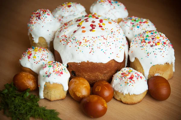 Homemade Easter cake for Easter with colored sprinkles, Easter picture, decorated craft eggs, natural painting of eggs with floral patterns. A lot of Easter cakes in a circle. On a wooden background.