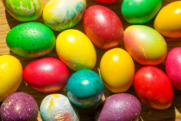 Red, yellow, green, violet, blue, turquoise, orange, multi-colored, motley colored Easter eggs on a wooden background
