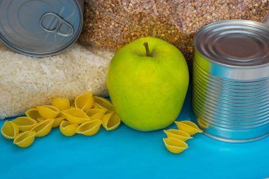  Teneke kutu, konserve yiyecek, makarna, mavi arka planda karabuğday. Yemek servisi. Yiyecek bağışı. Yemek dağıtıyor..