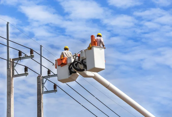 Electricistas reparando alambre de la línea eléctrica con cubo plataforma de elevación hidráulica — Foto de Stock