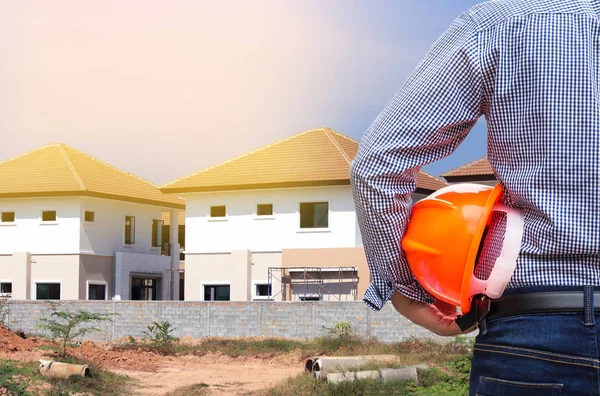 Engineer holding yellow safety helmet at new home building construction site — Stock Photo, Image