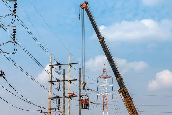 Electricistas trabajando en la altura en poste de energía eléctrica con grúa — Foto de Stock