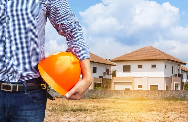 Resident engineer holding yellow safety helmet at new home building — Stock Photo, Image