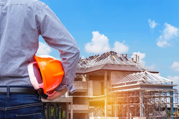 Resident engineer holding yellow safety helmet at new home building — Stock Photo, Image