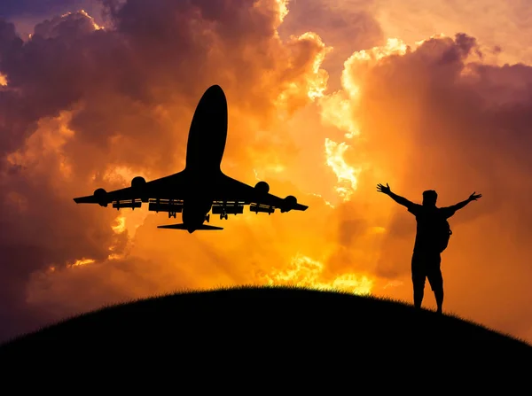 Silueta el hombre de pie levantó los brazos durante el despegue del avión en la puesta del sol — Foto de Stock