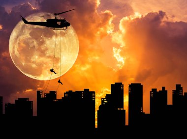 siluet asker eylem rappelling, helikopterden gökdelen günbatımı dolunay ile bina aşağı in