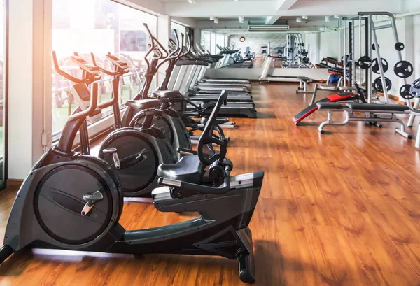 Fileiras de bicicletas estacionárias e esteiras e equipamentos de exercício físico na sala de fitness center — Fotografia de Stock