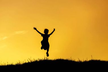 küçük kız günbatımı üzerinde atlama siluet   
