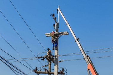 Tırmanma elektrikçi elektrik kolon üzerinde vinç ile çalışıyor. 