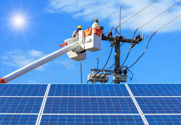 Electricistas reparando alambre de la línea eléctrica en cubo plataforma de elevación hidráulica con fotovoltaica en central solar —  Fotos de Stock