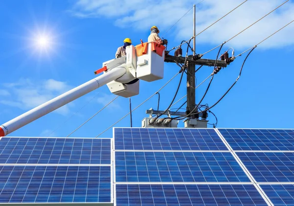 Electricistas reparando alambre de la línea eléctrica en cubo plataforma de elevación hidráulica con fotovoltaica en central solar —  Fotos de Stock