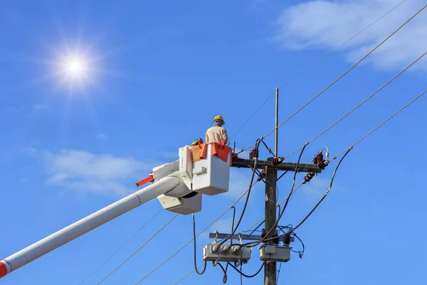 Electricistas reparando alambre de la línea eléctrica con cubo plataforma de elevación hidráulica — Foto de Stock