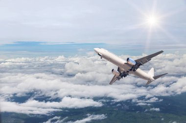 Beyaz ticari uçak içinde gökyüzü güneş ışığı ile beyaz bulutların üstünde yüksek yükseklik için uçup 