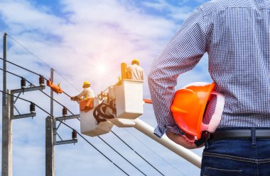 Elektrik elektrikçi elektrik kutubun kova hidrolik kaldırma platformu mavi gökyüzü arka plan üzerinde çalışma ile kask tutan mühendisi