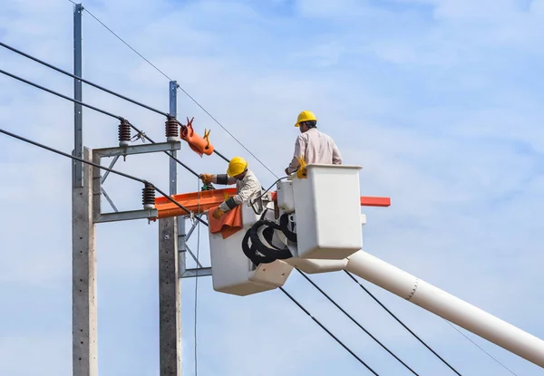 Tel ile kova hidrolik kaldırma platformu mavi gökyüzü arka plan üzerinde güç hattının tamir elektrikçiler