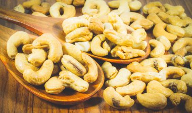 Ahşap arka planda kaju fıstığı kaşık yığınını kapat, kaju fıstığı sağlıklı bir diyet için mükemmel ve ilaç olarak kullanılabilir. konsept: diyet, fitness, tıp.