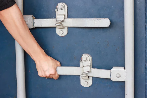 Perspective close up of hand is opening a blue container\'s door